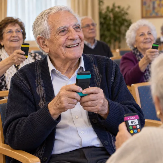 דייר עם מכשיר שמיעה מחייך ומחזיק את השלט בשתי ידיים