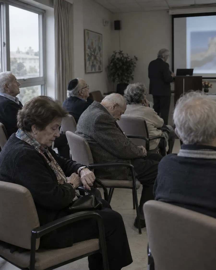 הרצאה משעממת בחדר פעילות: דיירים מנמנמים ומסתכלים בשעון